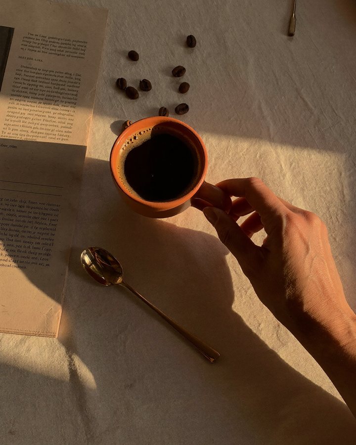 Une tasse vue du dessus sur une nappe de lin, grains de café et cuillère en laiton